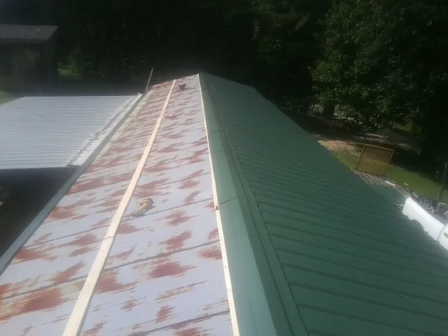 Old rusted panels beside newly installed green metal roofing — Wind Damage Roof Repair by Roofing Brothers in Wimauma